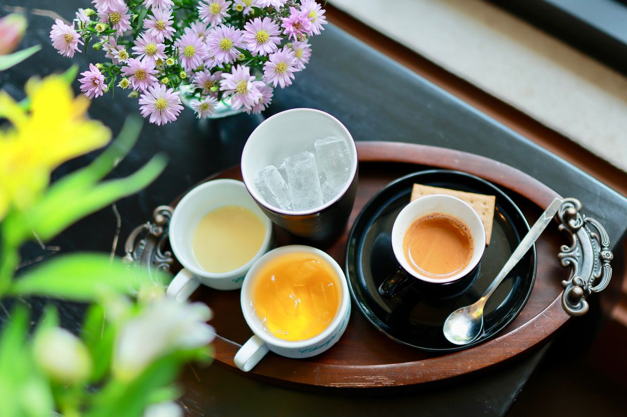 An elegant tray with various beverages and a bouquet of flowers offers a refreshing and inviting atmosphere.