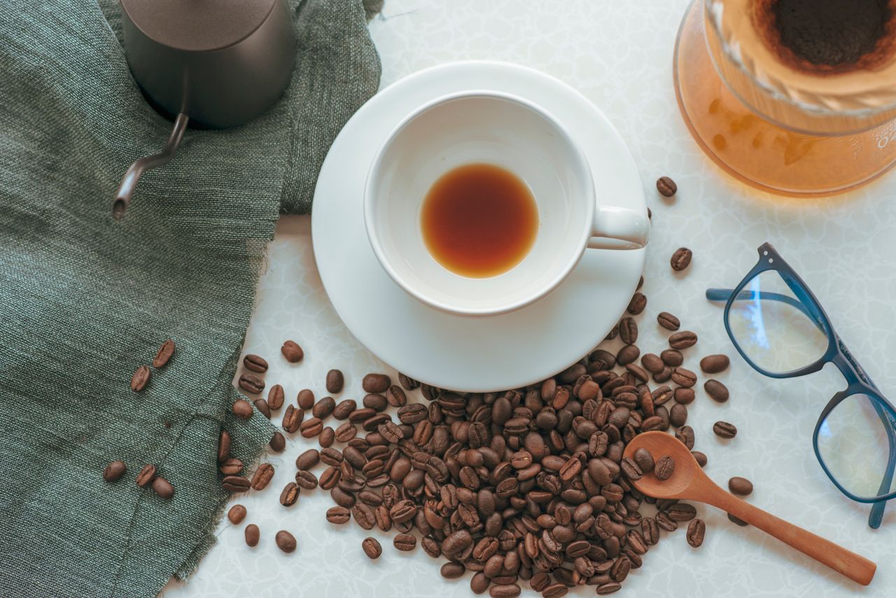 Aesthetic top view of a coffee cup with beans and accessories, perfect for coffee enthusiasts.